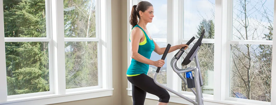 Woman exercising on an elliptical cross trainer at home